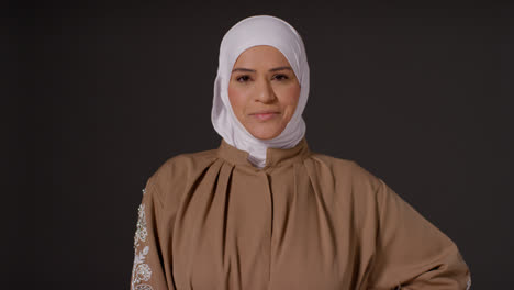 Retrato-De-Estudio-De-Una-Mujer-Musulmana-Sonriente-Usando-Hijab-Contra-Un-Fondo-Oscuro-Y-Liso